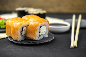 philadelphia maki rolls and eel unagi maki with soy sauce, pink ginger, wasabi on black background, asian food, japanese sushi set