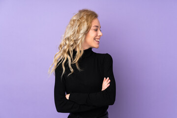 Young blonde woman isolated on purple background looking side