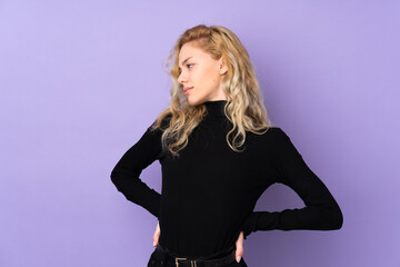 Fototapeta premium Young blonde woman isolated on purple background suffering from backache for having made an effort