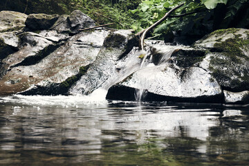 Mountain river surrounded by mountains. A waterfall flowing down from a Sheer cliffs . blue clear water of the river. Rocky stones and forest Alpine landscape