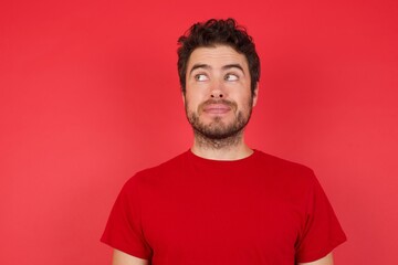 Fototapeta na wymiar Young handsome caucasian man wearing t-shirt over isolated red background, looking aside into empty space thoughtful