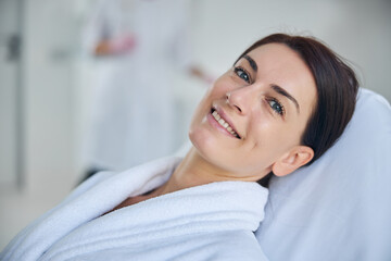 Obraz na płótnie Canvas Joyous woman in a bathrobe in a beauty salon