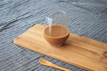 Latte coffee and wooden spoon standing on wood, on gray cover, isolated background