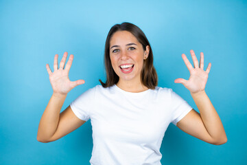 Young beautiful woman over isolated blue background showing and pointing up with fingers number ten while smiling confident and happy