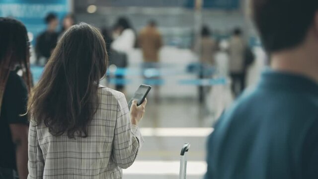 Girl travelling for a job purpose, waiting for a registration on flight. Back view of young businesslady in a middle of airport terminal. Woman waiting for a flight with suitcase during business trip.