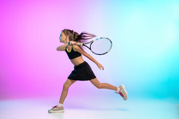 Unstoppable. Little tennis girl in black sportwear isolated on gradient background in neon light....
