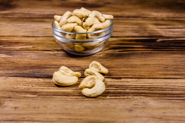 Glass bowl with raw cashew nuts on a wooden table