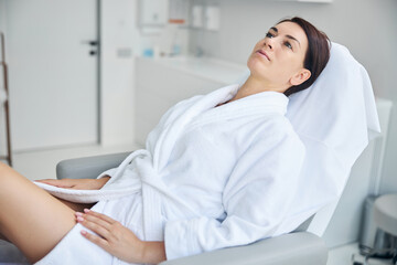 Attractive pensive adult spa client staring upward