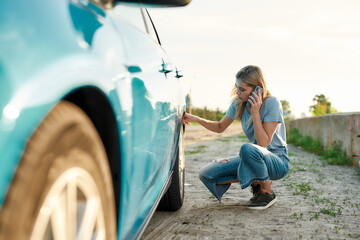 Attractive young woman looking sad, calling car service, assistance or tow truck while having...