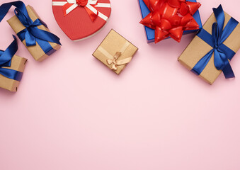 gift boxes wrapped in brown paper and tied with a red and blue bow, gifts on a pink background