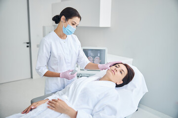 Qualified dermatologist in sterile gloves examining the patient