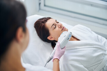 Qualified dermatologist performing an ultrasound facial treatment