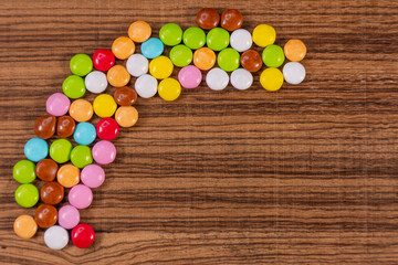 Small colorful chocolate tablets on exotic natural wood background