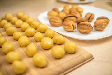 Small balls of cookie dough on a wooden Board and a plate of ready made cookies a Nut with boiled condensed milk