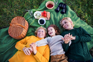 Top view of small girl with mother and grandmother having picnic in nature.