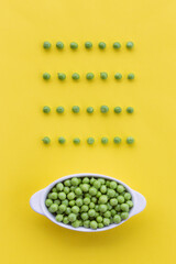 Fresh green peas on a bright yellow background. Creative layout with pattern peeled peas. Fun food. Graphic minimal concept.