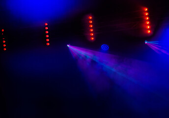 Stage lights. Several projectors in dark. A bright colored spotlight permeates the darkness. Light from the stage, rock concert. Lighting equipment. Several projectors on theatrical lighting system