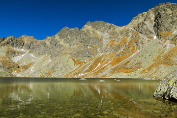 A lake under mountain peaks with clear sky in autumn