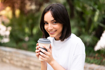 Young pretty woman holding coffee to take away at outdoors