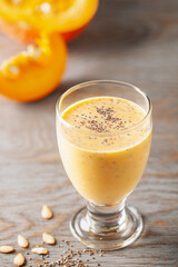 Healthy pumpkin smoothie with chia seed in glasses on wooden background.