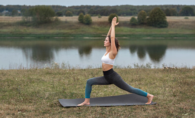 Fototapeta premium Young sporty woman doing fitness exercises near the river.