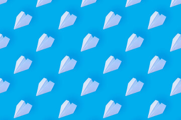 Pattern from white paper airplanes on a blue background. Creative concept of travel, flights..