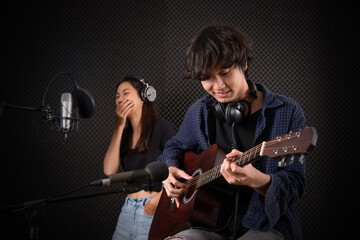 Young man playing guitar in music studio recording room