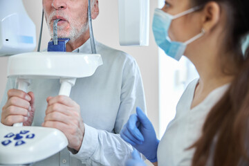 Obraz premium Female dental expert preparing an elderly man for dental x-ray