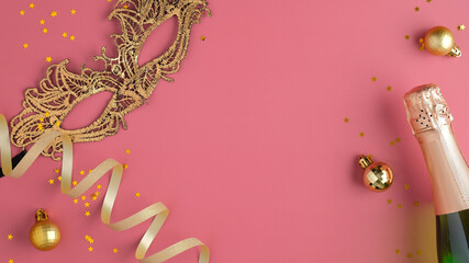 Masquerade golden mask, champagne bottle, confetti, balls decorations on pink background with copy space. Flat lay, top view. Christmas party concept.