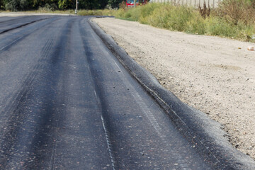 Damaged road, damaged chopped asphalt with potholes and spot. Very bad asphalt road with large trenche. Terrible technology of asphalt production in construction of road. Soft Asphalt melts from heat