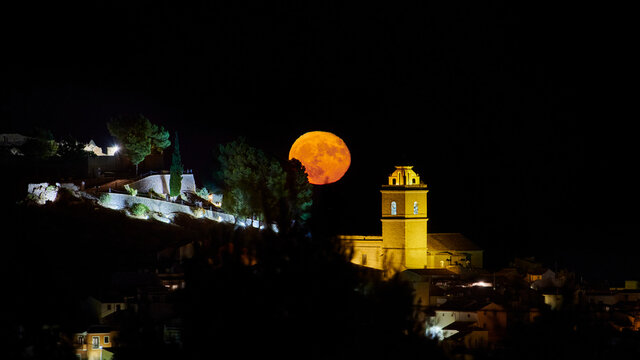 Full moon rise over town, in Polop de la Marina, Alicante, Spain, full moon next to church, moon rise on the Costa Blanca