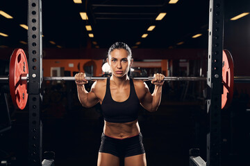Serious female athlete exercising with a barbell