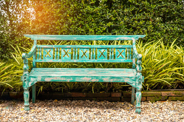 Green wooden bench in a city park in spring time and trees on background.