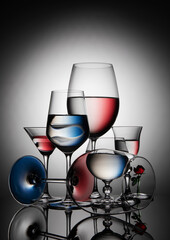 Six glass goblets on a colored gradient background