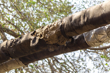 Overground heat pipes. Pipeline above ground, conducting heat for heating city. City aerial overground heating main in metal thermal insulation in residential city quarter. Open laying mains on poles