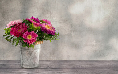pink leuchtende blumen im topf dekoration auf rustikalem holztisch vor alter verwischter wand