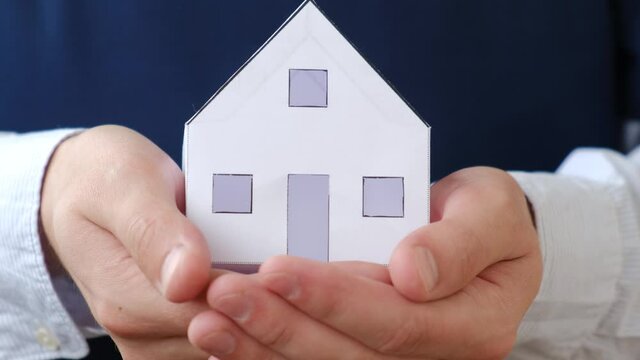 Small paper house in the hands of an insurance agent or realtor