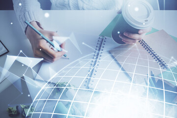 Double exposure of hands making notes with world map hologram and data theme icons. Concept of international network data.