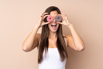Teenager girl over isolated background holding donuts in an eye
