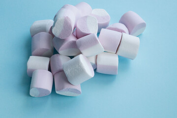 multicolored, soft sweets, candies, marshmallows, lies in a heap on a blue background. Place for inscriptions, text. Holiday sweets, sugar addiction, gift. Sweet decor, decoration. Multicolored Marshm