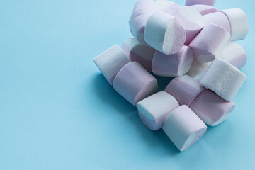 multicolored, soft sweets, candies, marshmallows, lies in a heap on a blue background. Place for inscriptions, text. Holiday sweets, sugar addiction, gift. Sweet decor, decoration. Multicolored Marshm