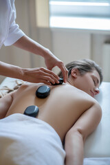 Obraz na płótnie Canvas Massage therapist putting stones on a womans back