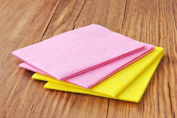 Multicolored micro fiber napkins on wooden background.