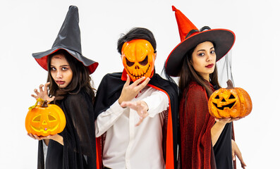Three young people dressed in different costumes holding pumpkin for Halloween, isolated on white