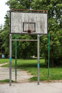 Old wooden basketball shield on the city sports field. A faded shabby basketball court for playing street basketball from a wooden shield and a metal ring of a  basket for playing