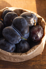 темно синяя слива на деревянном столе в утренних лучах солнца