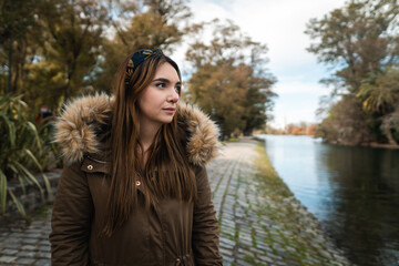 A young caucasian woman looking at lake on a beautiful park. Copy space