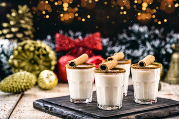 Obraz na płótnie Canvas hot christmas drink with decoration and christmas lights in the background, called eggnog, made with sugar, nutmeg, cinnamon and alcoholic drink