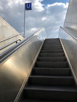 Munich, Bavaria / Germany - July 17, 2020: view over the escalator of a Munich underground railway station up to the sky with "U" sign symbolizing the subway