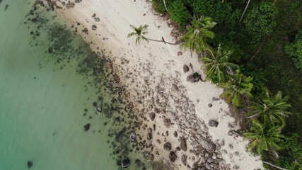 Stones on tropical beach near sea. From above rough boulders located on sandy beach near green palms and blue sea water on Koh Samui, Thailand. Dream beach drone view. Relax and holiday concept.